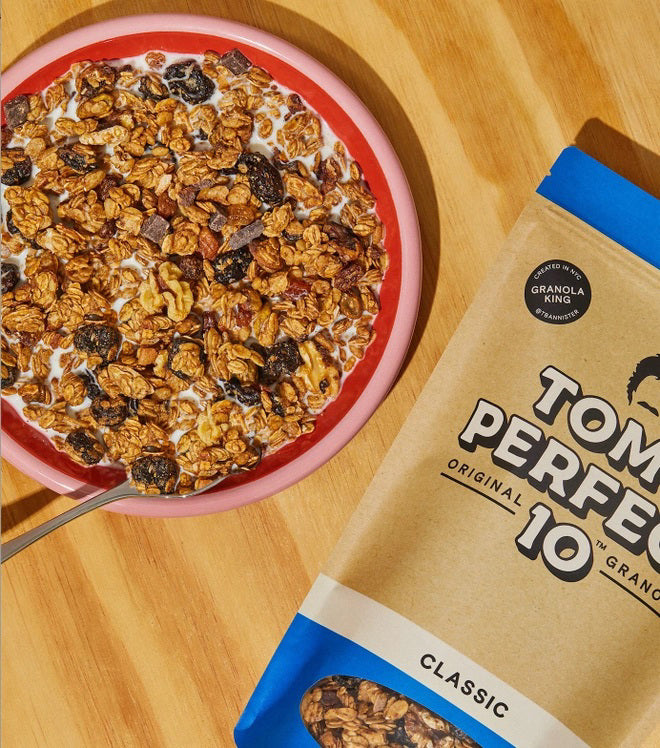 A beige and blue resealable pouch labeled "TOM'S PERFECT 10 - CLASSIC GRANOLA," featuring a transparent window at the bottom displaying the granola inside mixed with cherries. The pouch weighs 10 ounces (283.5 grams). A circular label says "Original Formula.