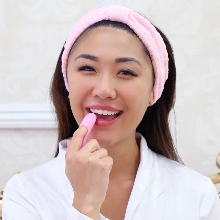 The Daily Concepts LIP SCRUBBER is a pink silicone facial cleansing brush designed with a textured bristle surface on one end and a convenient hole in the handle for hanging. This multifunctional, silicone-based brush features an oval cleansing head and an ergonomically curved handle, making it perfect for both effective facial cleansing and smooth, exfoliated lips.