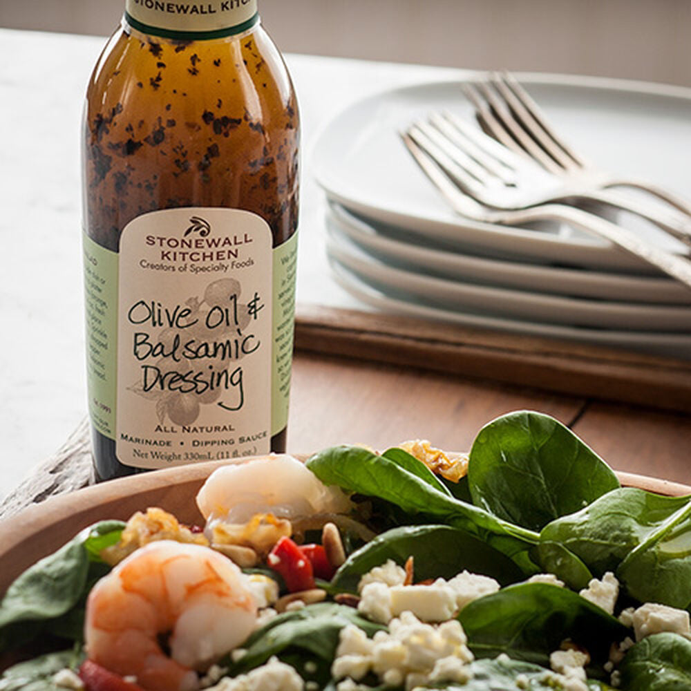 A bottle of STONEWALL KITCHEN- OLIVE OIL & BALSAMIC is displayed. The packaging includes a green label showcasing product details and is topped with a dark green cap. Ideal for drizzling over an antipasto salad, this bottle holds 330 ml (11 fl oz) of the delicious dressing.