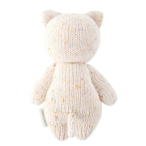 The CUDDLE + KIND - HANDMADE BABY KITTEN by CUDDLE & KIND is a knitted stuffed toy resembling a cat. It features small ears, black button eyes, and a stitched smile. Made from 100% cotton yarn, the light beige kitten has multicolored specks throughout the fabric for a textured appearance. Each purchase of this hand-knit baby animal supports fair trade income.