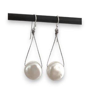 The ANN LIGHTFOOT White Freshwater Pearl Disc Drop Earrings feature sterling silver earwires, with large, round white freshwater pearls gracefully hanging from a sleek black rod for an elegant look.