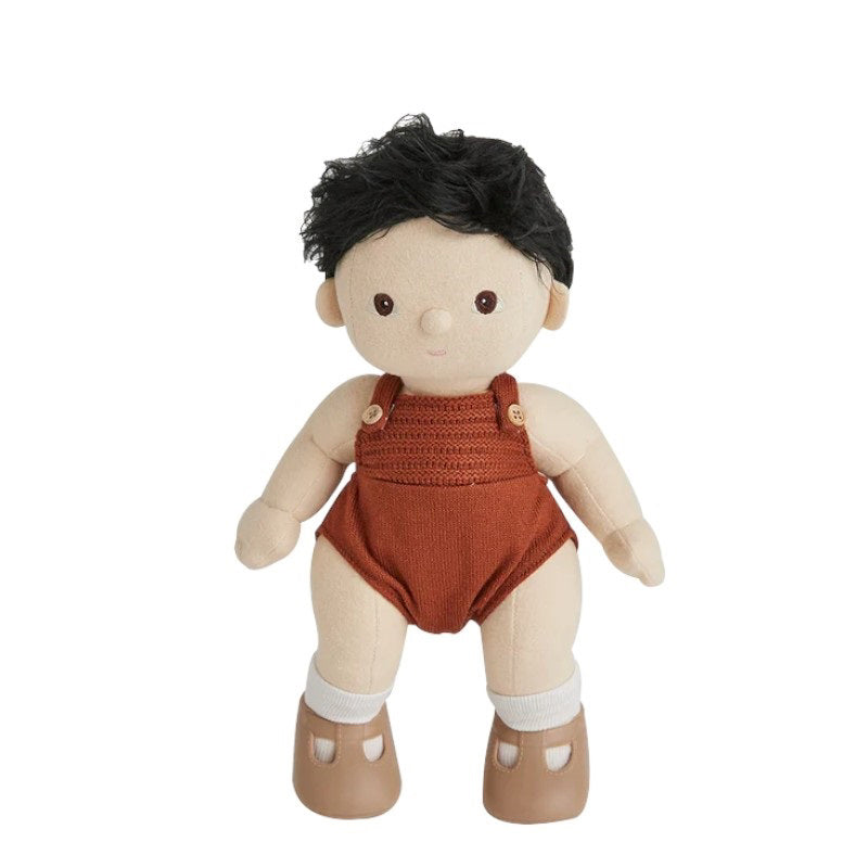 A DINKUM DOLL from OLLI ELLA USA features soft brown hair and comes dressed in a white knit romper paired with brown shoes. This charming doll has an embroidered face with brown eyes, a small nose, and a gentle smile. Its posable body makes it perfect for imaginative playtime, and it is posed standing upright.