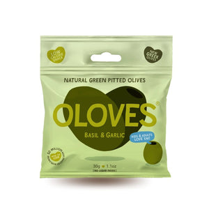 A light green packet of OLOVES - BASIL & GARLIC natural green pitted Greek olives by POSHI, flavored with basil and garlic. The packaging showcases a cartoonish olive graphic and emphasizes: "Low Calorie Snack," "New Greek Olives," "Kids & Adults Love 'Em," "Gluten-Free Vegan Snacks," and "30g | 1.1oz.