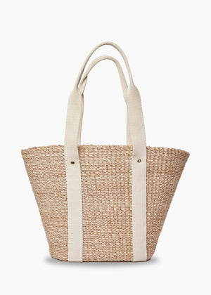 The KAYU Toci Medium Tote by KAYU features a wide, woven abaca straw body with sturdy cotton handles. Its minimalist design is highlighted by two vertical beige straps on both sides, combining style and functionality.