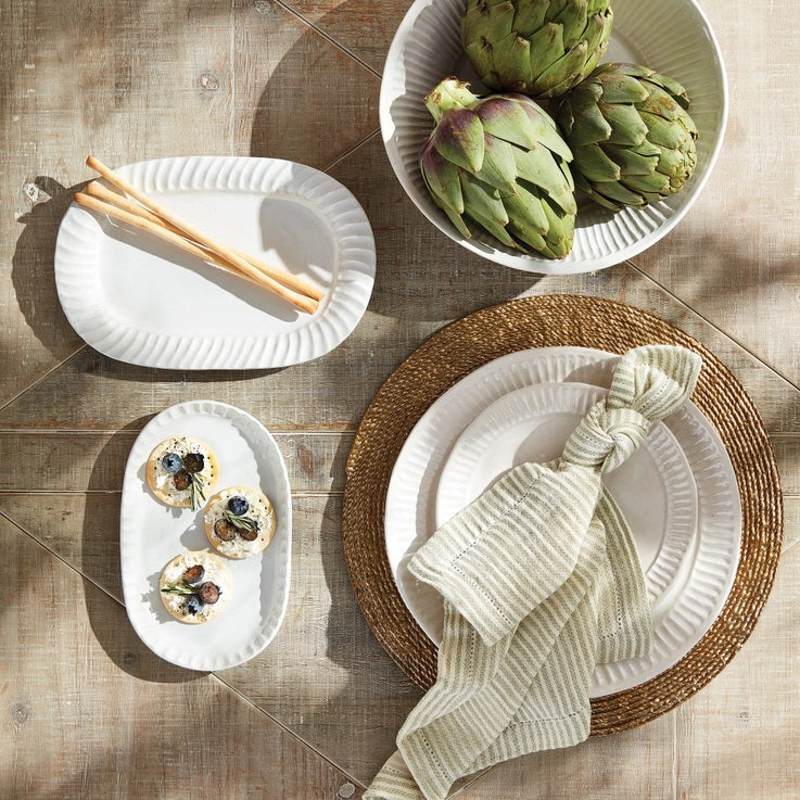 The PRIM NAPKIN by NAPA HOME AND GARDEN offers a neatly arranged set of off-white and beige striped fabric napkins, designed to be machine washable for your convenience. Made from lightweight fabric, these napkins display a simple and elegant pattern of evenly spaced vertical stripes. The set is neatly folded with one napkin draped over the top to showcase their texture and design beautifully.