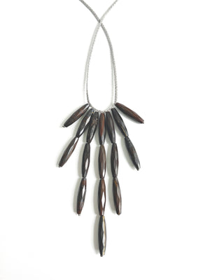 The ANN LIGHTFOOT - BRONZITE DEMI-FRINGE NECKLACE showcases elongated, faceted brown beads arranged in a cascading fringe design on a delicate grey cord. Lustrous bronzite droplets are elegantly displayed in two symmetrical tiers, and its adjustable ties guarantee an ideal fit for every wearer.