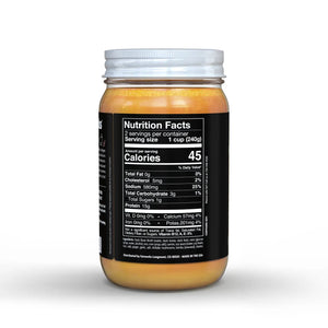 A jar of FATWORKS - RAMEN DUCK BONE BROTH is shown. The clear jar with a white lid reveals golden yellow contents. Labeled "FATWORKS," it highlights being protein-packed and a rich collagen source, perfect for keto diets. Net weight is 15 oz (425g).