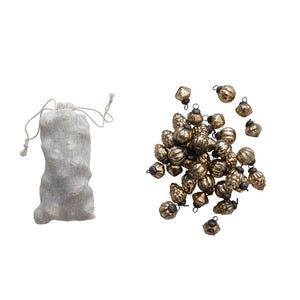 The GLASS ORNAMENT BAG SET by CREATIVE COOP features a drawstring fabric bag placed next to a gleaming assortment of metallic-gold ornaments, including acorns and pumpkins with an antique gold finish, all arranged on a textured light surface.