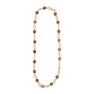 The CAPUCINE DE WULF - EARTH GODDESS LINK NECKLACE WITH TEAK by CAPUCINE DE WULF features alternating brown teak beads and intricate gold chain links. This versatile piece of jewelry is finished with a decorative gold clasp, giving it a sophisticated and elegant look.