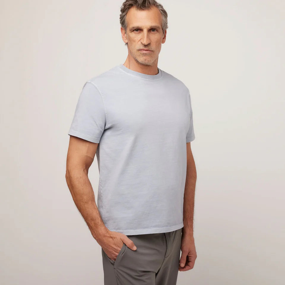 A middle-aged man with short gray hair wears the TILLEY Mid Weight Sun Washed T-Shirt in Ice Blue, standing against a plain light background and looking confidently at the camera.