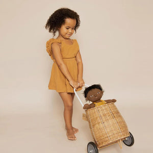 A DINKUM DOLL from OLLI ELLA USA features soft brown hair and comes dressed in a white knit romper paired with brown shoes. This charming doll has an embroidered face with brown eyes, a small nose, and a gentle smile. Its posable body makes it perfect for imaginative playtime, and it is posed standing upright.