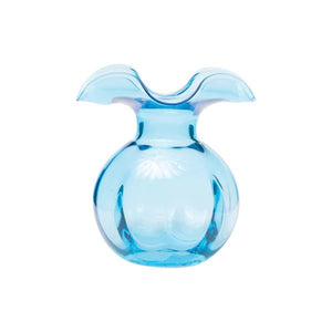 The VIETRI Hibiscus Bud Vase in Aqua features a sculptural design with a curvy, wide top and rounded body. Its translucent blue material reflects light beautifully, evoking the elegance of a blooming hibiscus flower and showcasing the artistry of Tuscan artisans.