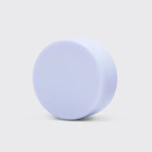 A light purple solid conditioner bar sits atop a white rectangular box. The box, labeled "KITSCH Purple Toning Solid Conditioner Bar," highlights that the biotin-infused product, weighing 2.7 oz (77g), neutralizes brassiness in blonde and highlighted hair.