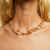 The GAS BIJOUX - ROSARIO NECKLACE by GAS BIJOUX is a double gold plated necklace featuring alternating twisted gold links and small mother-of-pearl beads. It boasts an elegant circular clasp, with evenly spaced strands that create a balanced, luxurious appearance. The necklace is arranged in a circular shape for display.