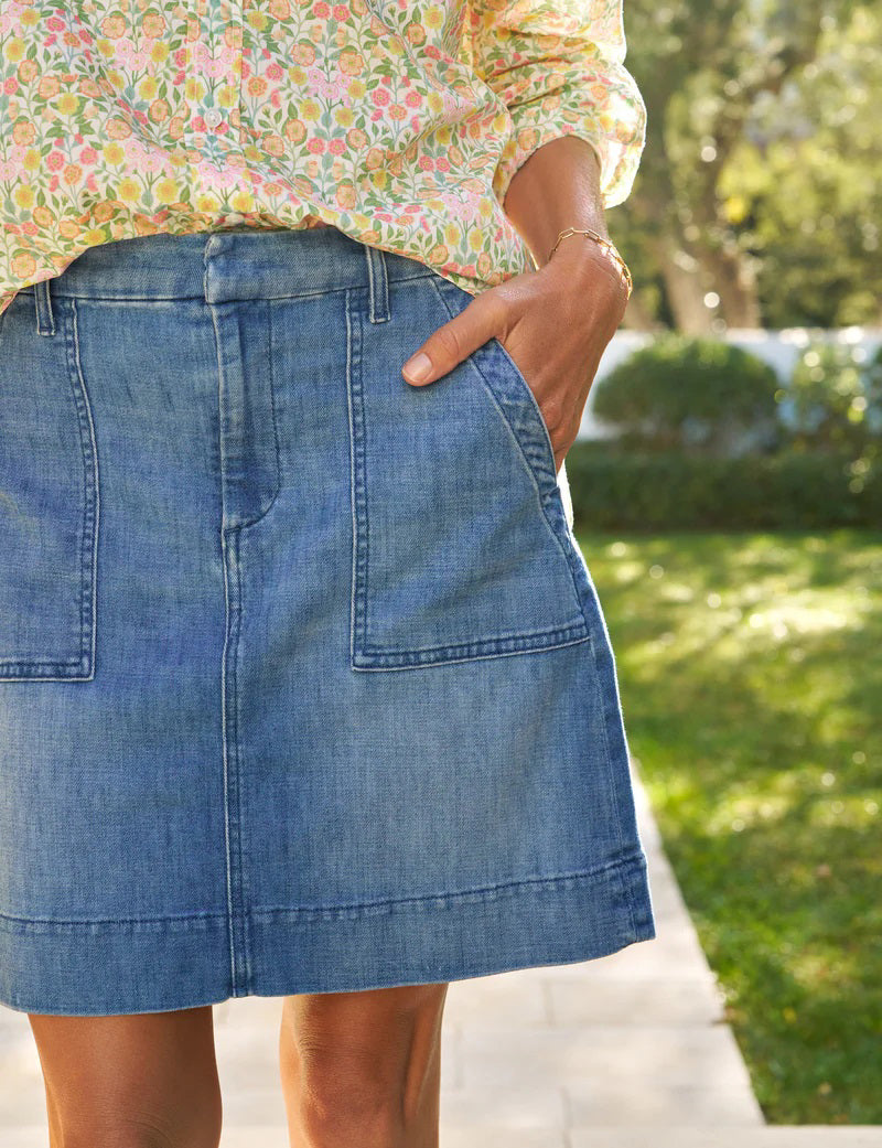 The FRANK &amp; EILEEN Jameson Utility Skirt in Italian Dream Light Denim 1968 Wash is a blue mini skirt with utility pockets, belt loops, and a front zipper closure, shown against a white background.
