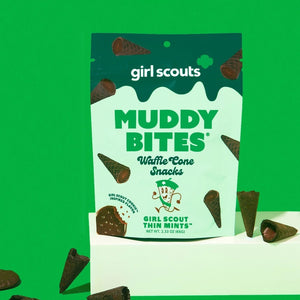 Image of a MUDDY BITES- THIN MINT WAFFLE CONES product package. The green package emphasizes the Girl Scout Thin Mints flavor, featuring mini waffle cones filled with mint chocolate and dark chocolate. It also showcases nutrition facts, GMO-Free and Kosher certifications, and resealable packaging for freshness. Founders: Jared and Tyler.