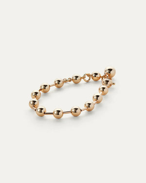 The JENNYBIRD Celeste Bracelet displays a series of gold beads with a high polish finish, connected by a fine chain, all set against a white background. A larger bead functions as the clasp for this elegant piece.