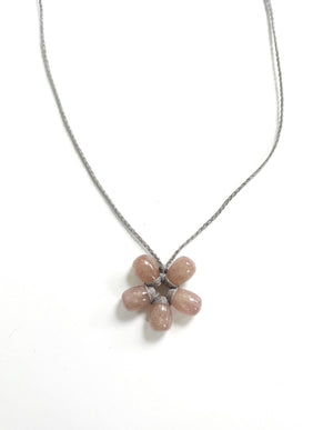 The ANN LIGHTFOOT Petite Sunstone Flower Necklace features a flower-shaped pendant with five pink stone petals and a central white stone on a dark setting. It has a delicate silver chain and adjustable nylon ties for the perfect fit.