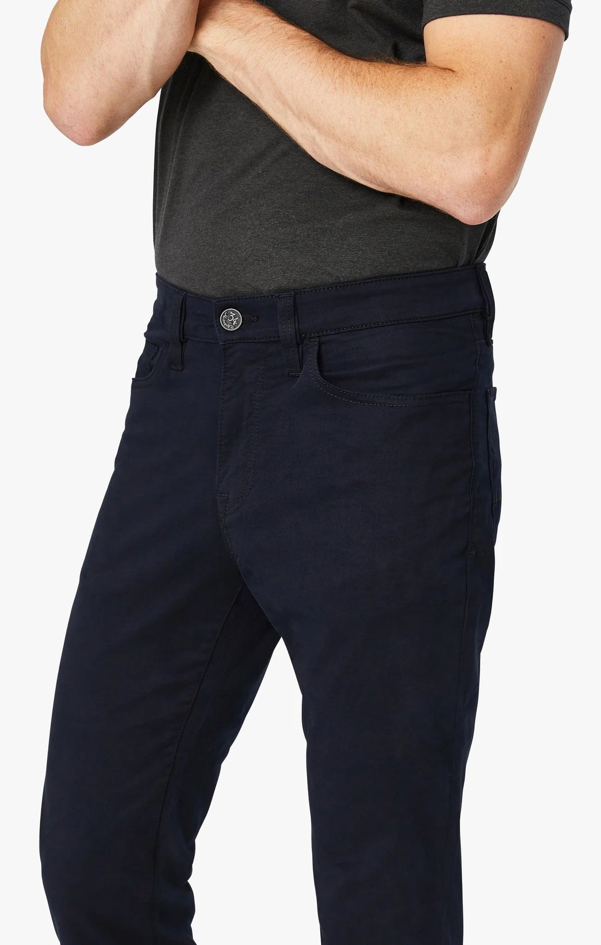A man stands with his arms crossed, wearing a dark gray T-shirt and 34 HERITAGE - CHARISMA RELAXED STRAIGHT PANT IN NAVY TWILL, with only his upper body and waist shown against a plain white background.