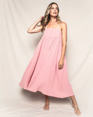 The PETITE PLUME - GAUZE SERENE LOUNGE DRESS, part of the luxury Gauze Collection by PETITE PLUME, is a pink sleeveless maxi dress with thin spaghetti straps and a square neckline. This sundress features a loose, flowing design with gathered fabric under the bust for a relaxed and airy look. Made from lightweight cotton gauze, it feels breezy and textured.