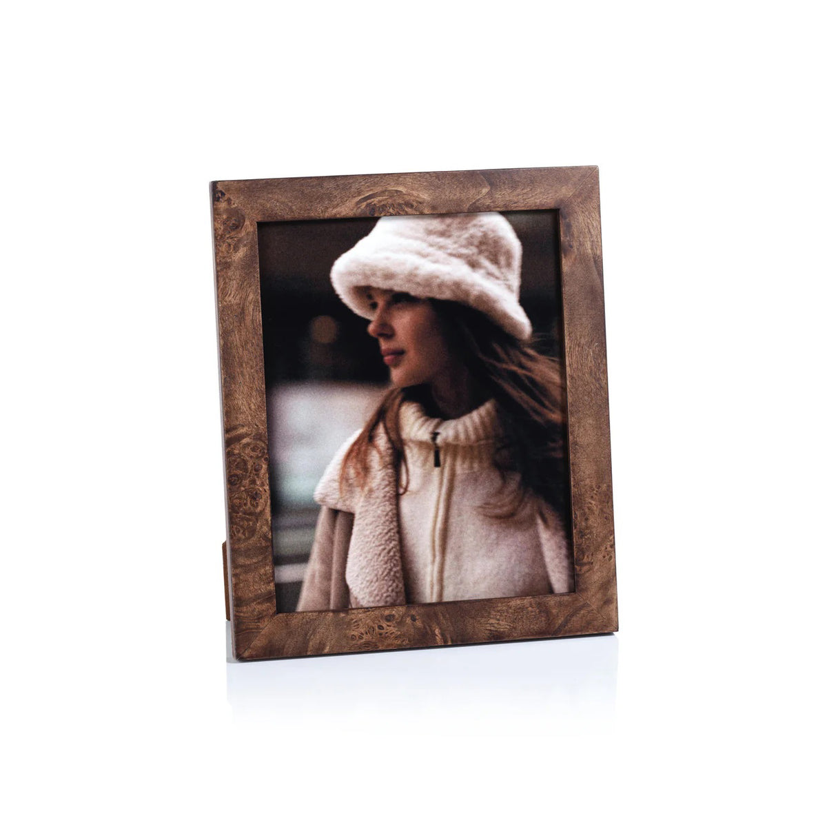 The ZODAX BURL WOOD PHOTO FRAME 8X10 showcases a portrait of a woman in a white fuzzy hat and cream coat, gazing sideways against a softly blurred backdrop.