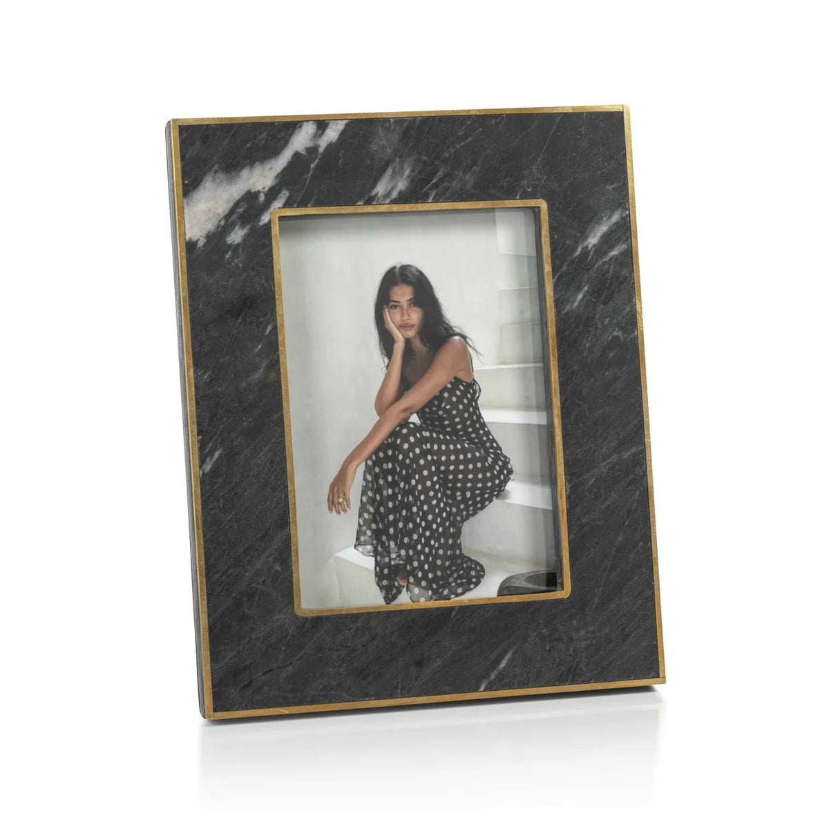 The ZODAX RENNES GRANITE PHOTO FRAME 5X7 features a rectangular black marble design with gold trim, showcasing a photo of a woman in a polka dot dress on white steps. This elegant frame adds sophistication to any space.