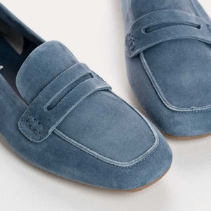 The REQINS - HEMA suede loafer in Blue Jean features a classic silhouette, minimalist design, penny strap, and brown soles, shown against a plain white background.