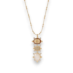 The GAS BIJOUX TIKI NECKLACE is a gold-plated necklace featuring a pendant with three gemstones in oval, rectangle, and teardrop shapes. These stones are set in a vertical arrangement within a gold frame, resembling a lucky charm, and hang from a gold chain adorned with small bead-like elements.