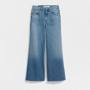 The FRANK & EILEEN Galway Gaucho Jean in the 1972 Wash offers a high-waisted, wide-leg design with a subtle faded effect and classic five-pocket styling, perfectly embodying the spirit of Italian Dream Denim. Featuring a raw hem for that iconic gaucho-style, these light blue jeans are showcased against a lightly textured background.