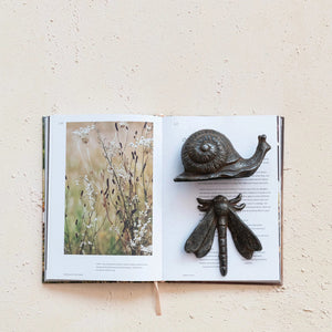 The CAST IRON SNAIL by CREATIVE COOP is a small, dark sculpture featuring a spiraled shell and extended antennae, displayed on a plain white background. The rust finish adds a touch of vintage charm, while the texture and detailing give it a realistic appearance, making it perfect for home decor.