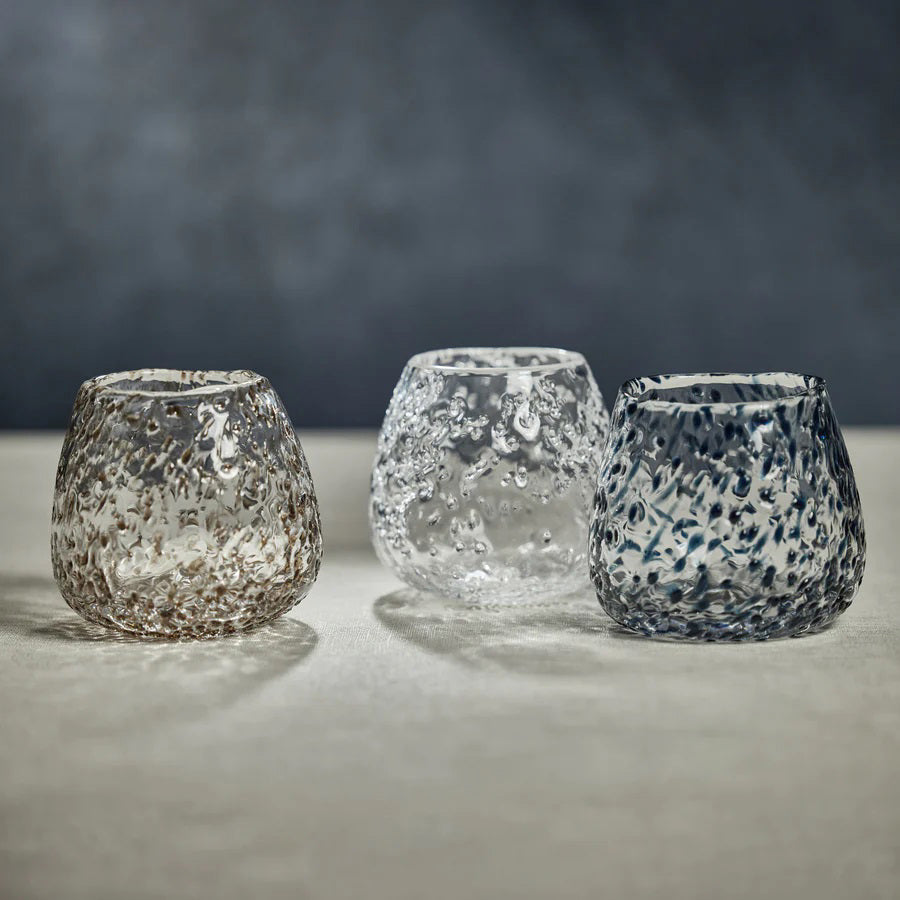 Presenting the SCISSOR CUT GLASS VASE by ZODAX: This clear, textured glass vase features a rounded shape with a slightly wider base, measuring 5 inches by 4.5 inches (12.7 cm x 11.43 cm). Its bubble-like patterns reflect light beautifully on a white background, adding a decorative, artisanal touch to any surface.