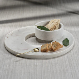 The ZODAX MARBELLA Marble Chip & Dip Server is a round, white marble lazy Susan with a smooth finish, featuring a smaller round marble bowl in the center. Measuring 14 in x 2 in (35.56 cm x 5.08 cm), this server has subtle gray veining and exhibits a minimalist design.