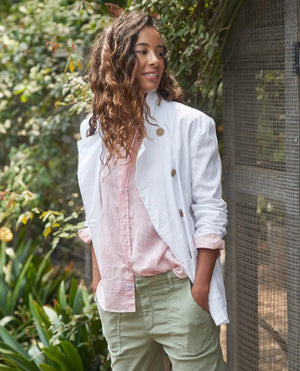 A white double-breasted Belfast English Peacoat by FRANK & EILEEN featuring two front pockets, brown buttons, and a notched lapel collar. The blazer showcases rolled-up sleeves and a stretchy fit for added comfort, with an inner tag reading "Frank & Eileen." Displayed against a light textured background, it exudes California cool vibes.