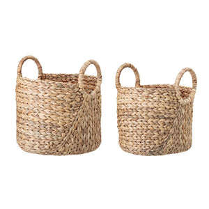 The SEAGRASS BASKET W HANDLES by CREATIVE COOP comprises two round, handwoven seagrass baskets featuring integrated circular handles. These rustic picnic essentials come in slightly varying sizes and are empty. The handles extend upward from the basket's rim, ensuring easy carrying and mobility.