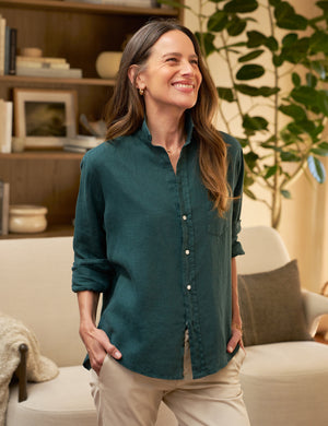 The FRANK & EILEEN's Eileen Relaxed Button-Up Shirt in Washed Linen Forest is displayed in the image. This green, long-sleeve shirt features a front pocket and a relaxed fit with bust-flattering button placement. The sleeves are rolled up to mid-forearm and all buttons are fastened, exuding California effortlessness against a plain white background.