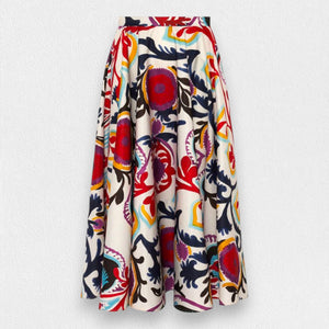 The SFIZIO - FRIDA SKIRT by SFIZIO is a mid-length, versatile garment with a white background that showcases a bold and colorful abstract floral pattern in shades of red, blue, yellow, and green. Made in Italy, this skirt features pleats and a flared silhouette for an effortlessly chic look.