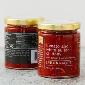 Two jars of LE BON MAGOT - TOMATO AND WHITE SULTANA CHUTNEY by LE BON MAGOT LLC on a gray countertop. Labels show nutritional information and ingredients like tomatoes, sugar, dried sultanas, and spices. Jars have gold lids and a 7oz (198g) capacity.