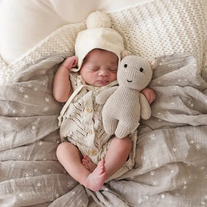 The CUDDLE + KIND - HANDMADE BABY HIPPO by CUDDLE & KIND is a charming, hand-knit stuffed toy featuring a smiling beige hippopotamus with black eyes and small round ears. Its soft, textured appearance and simple, cute features make it an ideal baby shower gift.