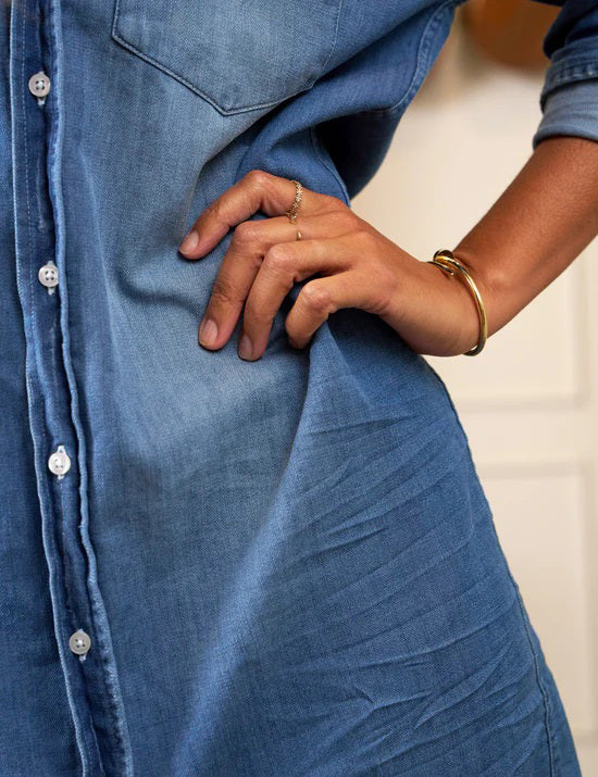 The FRANK &amp; EILEEN Rory Maxi Shirtdress in Famous Denim is a full-length button-up dress featuring a collar, rolled-up sleeves to mid-length, and a single chest pocket. Its sleek, minimalist design embodies that California chic look against a plain white textured background.