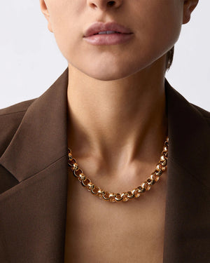 The JENNYBIRD RODIN NECKLACE is a high-polish gold rolo chain with interlocking round links arranged in an elegant circular pattern, beautifully showcased on a light background.