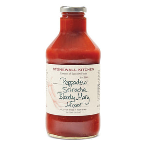 A clear glass bottle labeled "STONEWALL KITCHEN - PEPPADEW SIRACHA BLOODY MARY MIX" features a hand-drawn chili pepper and text proclaiming it gluten-free and non-GMO. Inside, the red liquid promises a flavorful blend that will elevate your Bloody Mary with a spicy sriracha kick.