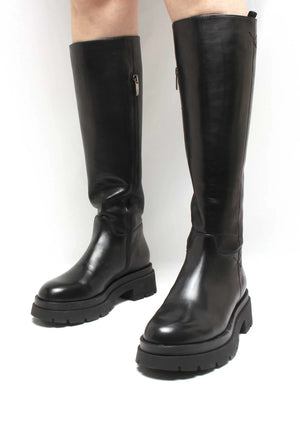 The TALL LEATHER BOOT by MICHELE LOPRIORE features two white, genuine leather knee-high boots with black soles and black stitching accents. The boot on the left is shown from the back, highlighting a full-length zipper, while the one on the right is presented from the side. Both minimalist-designed boots are showcased against a plain background. Made in Italy.