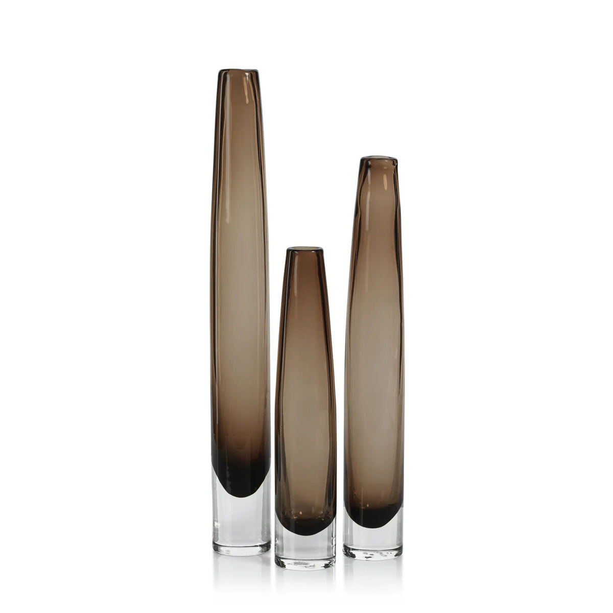 The ZODAX TATE Slim Glass Taupe Vase - Tall features a narrow cylindrical design in smoky brown glass with a clear base, ideal for display on a glass shelf against a plain white background.