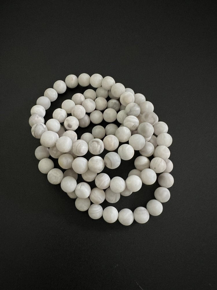 The matte white agate beads of the ANN LIGHTFOOT elastic cuff bracelet create a stunning coiled design, elegantly displayed on a white background.