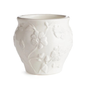 A decorative scene featuring the BLOSSOM CACHEPOT by NAPA HOME AND GARDEN, a tall white ceramic vase adorned with floral stem designs, filled with blooming white flowers on long stems. Next to it is a shorter, similarly patterned white ceramic jug on a wooden table with a gray surface, creating an elegant look.