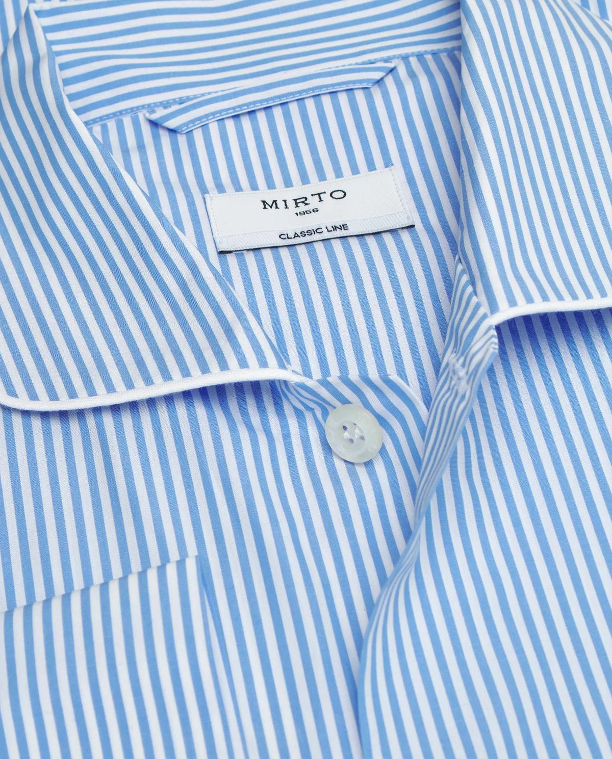 A man stands barefoot facing away from the camera in a MIRTO 1956 - BLUE STRIPE COTTON POPLIN PAJAMA SET, featuring long sleeves and pants—a timeless men’s sleepwear piece by MIRTO 1956, shown against a plain light background.