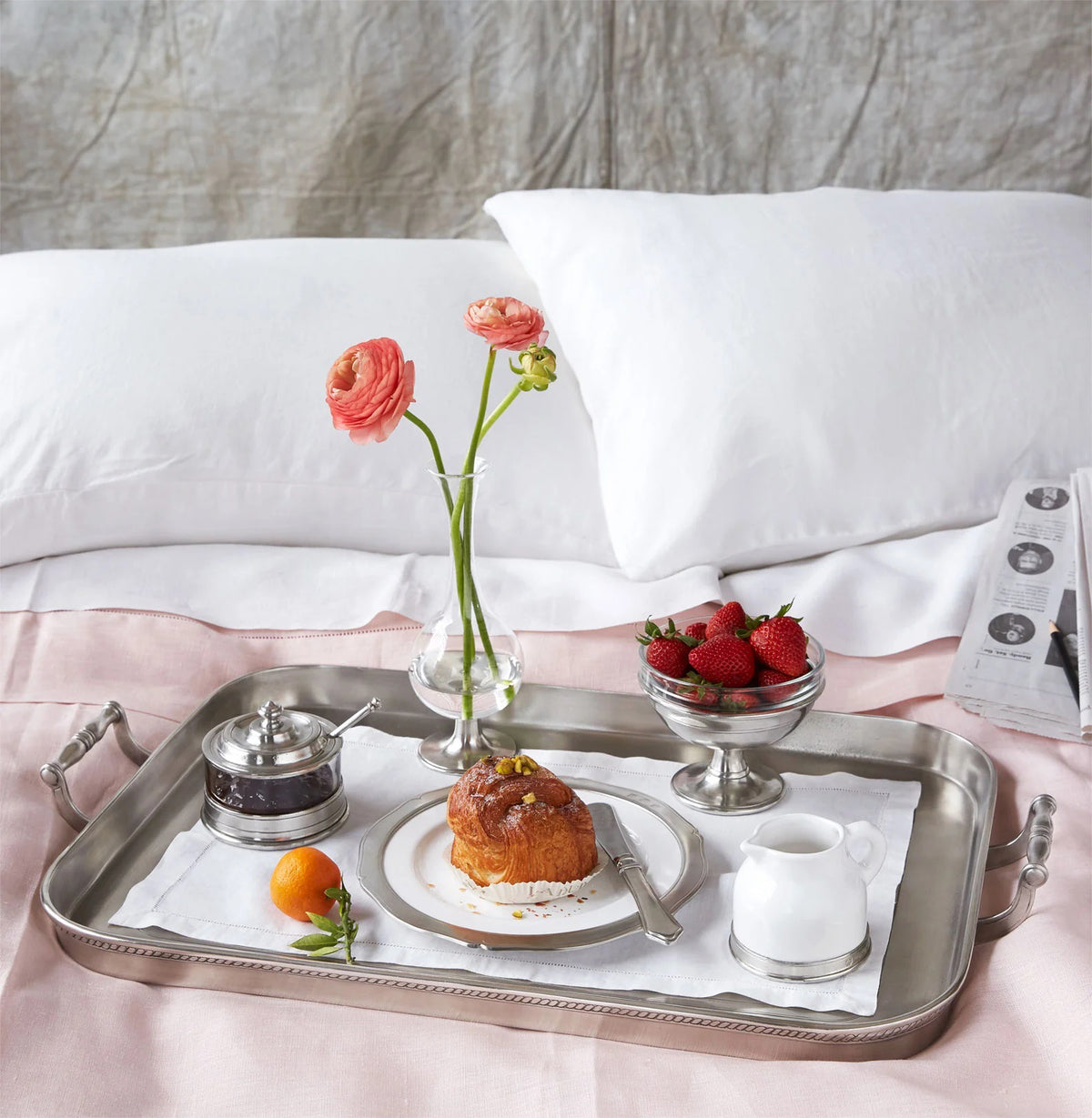 A single light pink peony with green leaves in a MATCH - PEWTER FOOTED GLASS VASE by MATCH, partially filled with water and set against a white background.