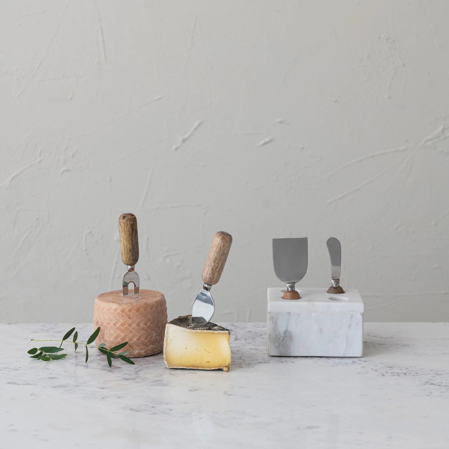 The MARBLE CHEESE SERVER STAND by CREATIVE COOP elegantly displays four stainless steel cheese knives with wooden accents. With artisanal design and unique blades, these servers stand upright against a white backdrop, epitomizing modern elegance in serve ware.