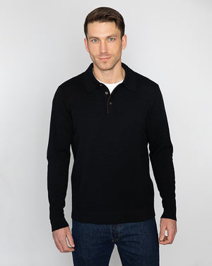 A person wearing a beige KINROSS CASHMERE SUEDE TRIM POLO over a white shirt and dark blue jeans stands with their left hand in their pocket against a plain white background.