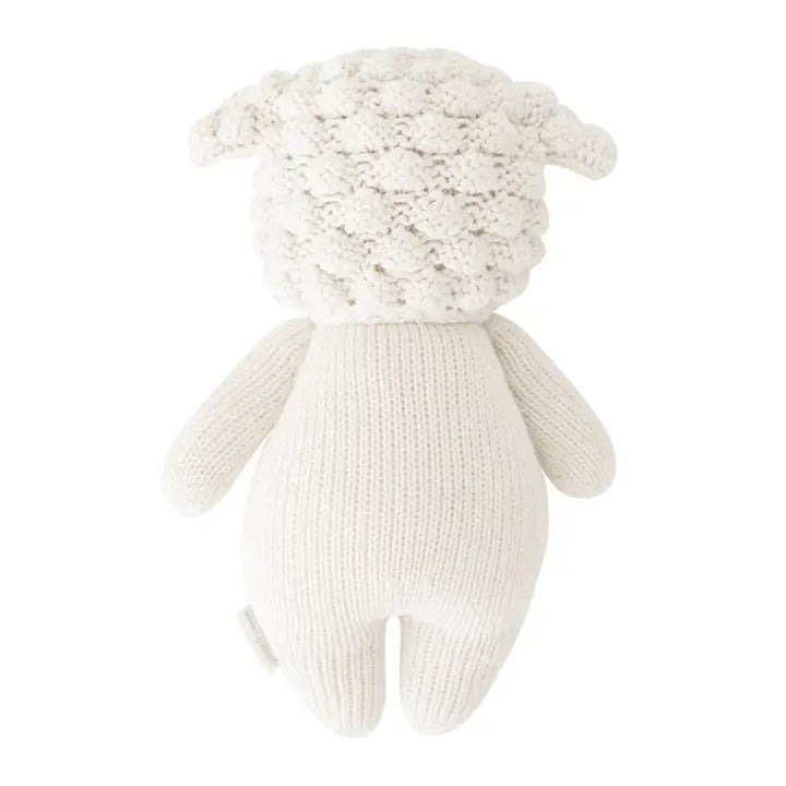 Introducing the CUDDLE + KIND - HANDMADE BABY LAMB by CUDDLE &amp; KIND. This delightful knitted stuffed toy is crafted from 100% cotton yarn and features a white, wool-like texture. It has adorable black eyes, a smiling mouth, and small round ears. The toy’s body boasts a simple design with a smooth and plush finish. Perfect as one of your fair trade baby gifts!